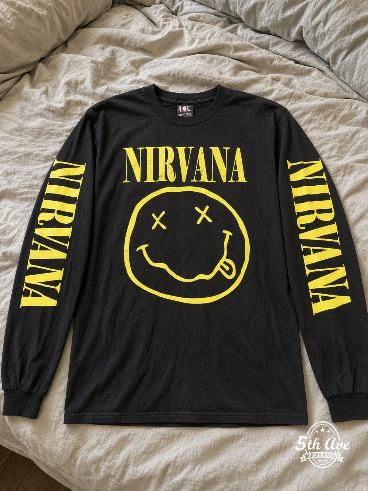 ETS LS 27 Nirvana Smiley Face long sleeve vintage tee laid on a bed