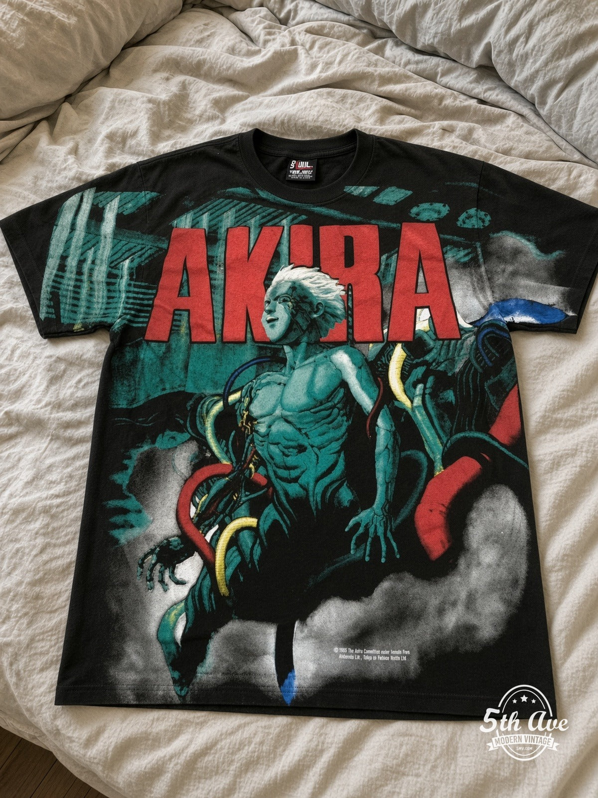 Akira Teal Character all over print vintage tee laid on bed