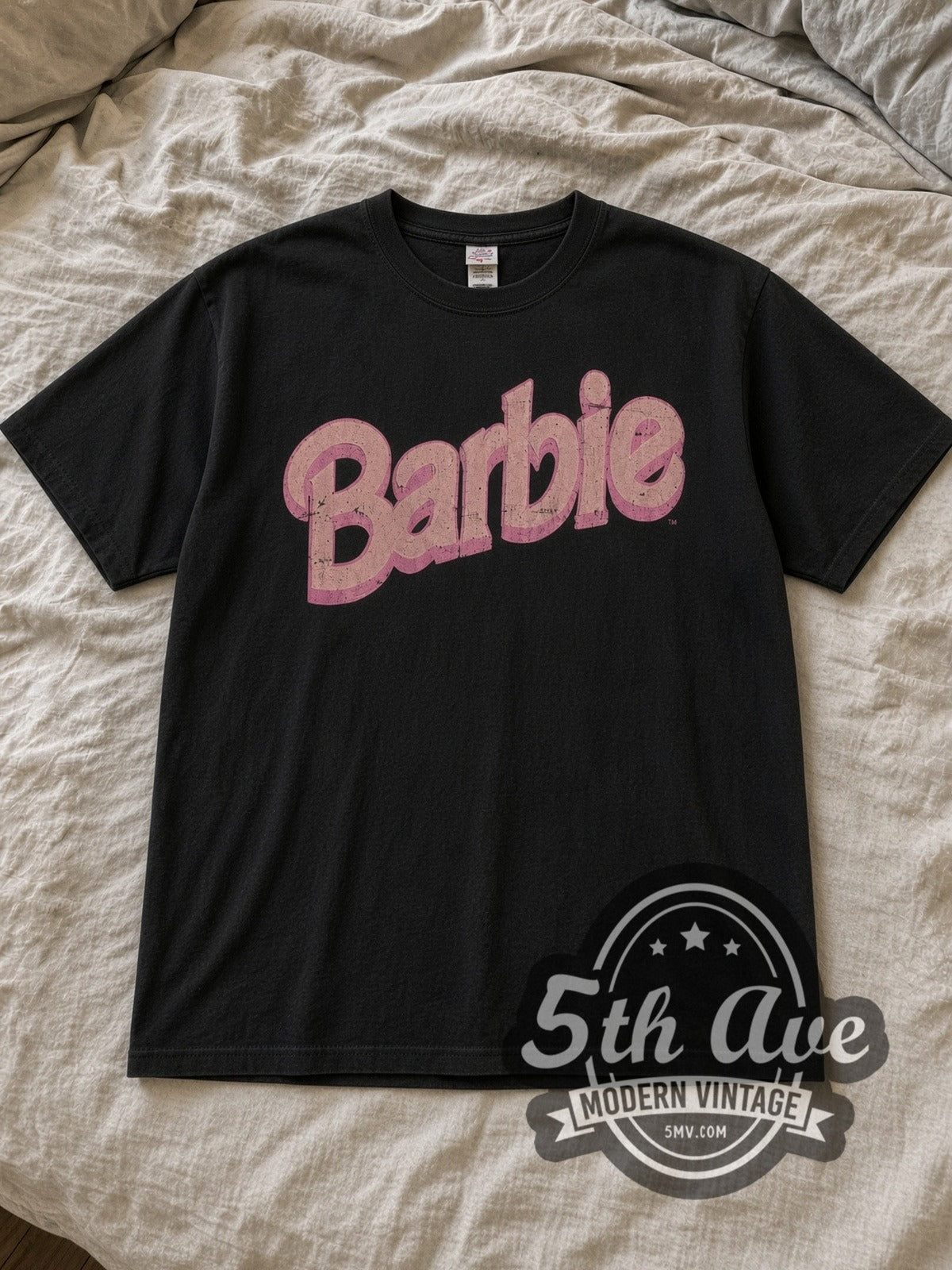Black Barbie Pink Heart Vintage Cartoon T-Shirt laid flat on a linen bed