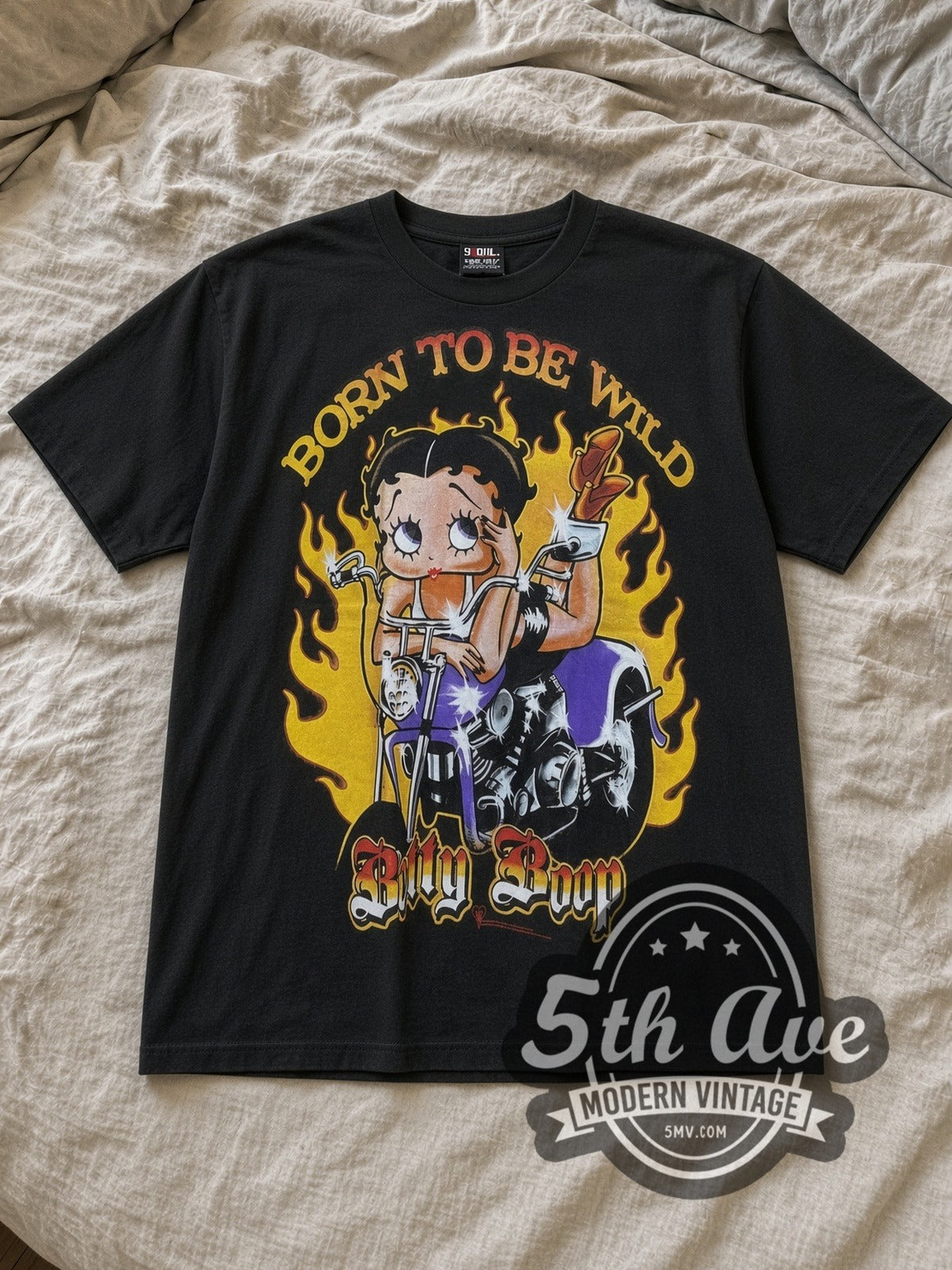 Black Betty Boop Born to Be Wild Biker Vintage Cartoon T-Shirt laid flat on a linen bed
