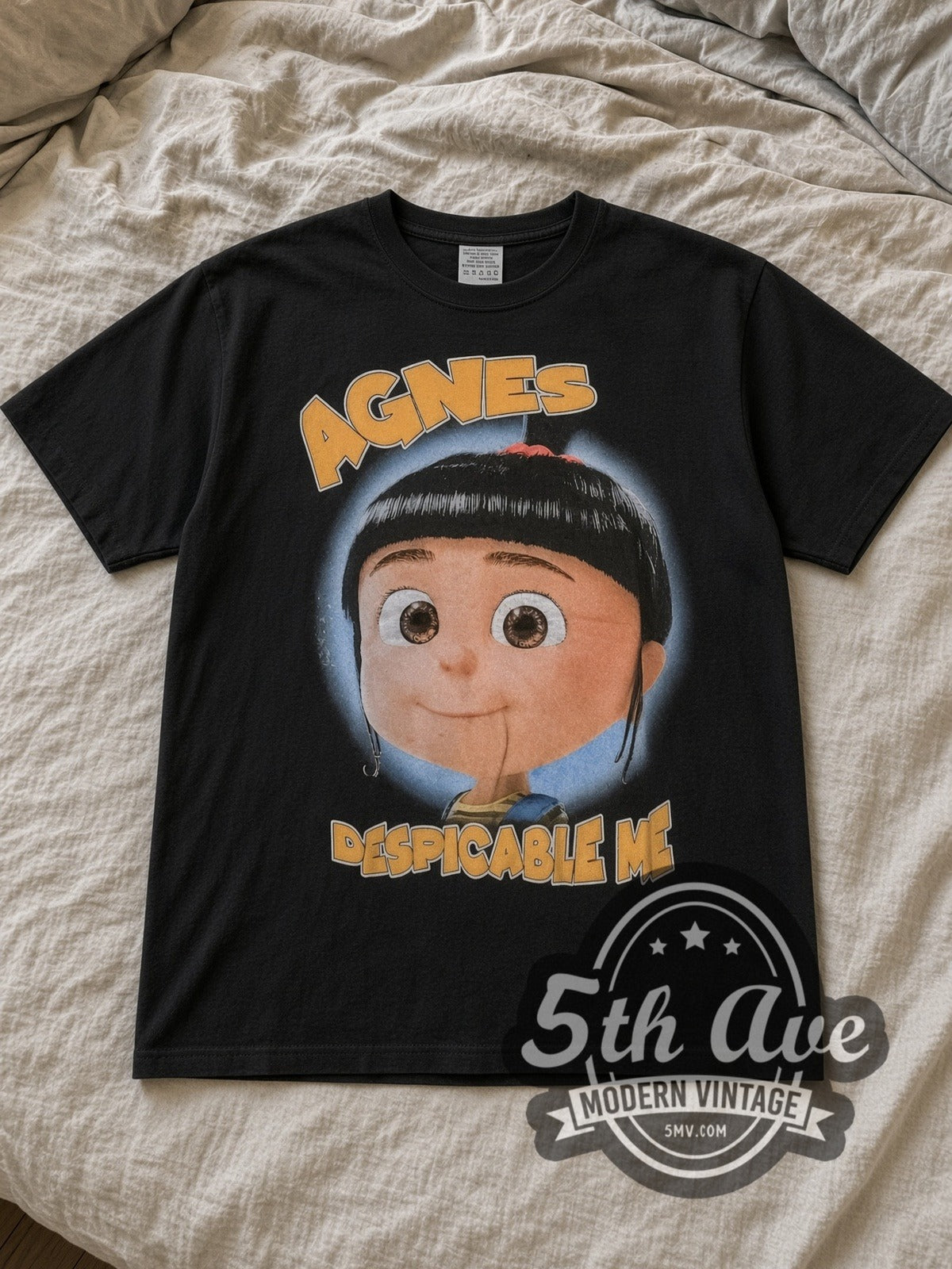Black Despicable Me Agnes and Her Unicorn Adventure Vintage Cartoon T-Shirt laid flat on a linen bed