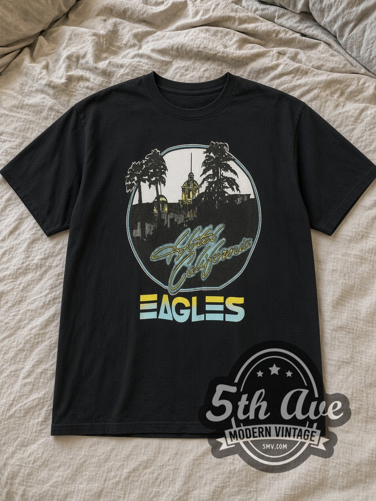 Black Eagles Hotel California Vintage Band T-Shirt laid flat on a linen bed