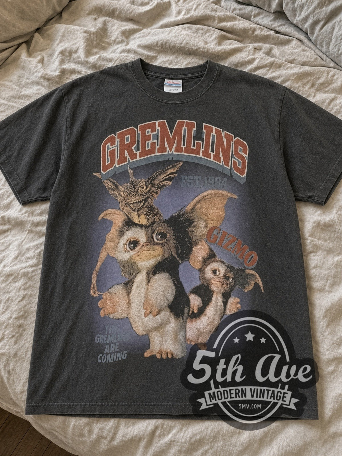 Faded Black Gremlins Est. 1984 Gizmo & Stripe / Gizmo in a Box vintage movie tee laid flat on linen bed
