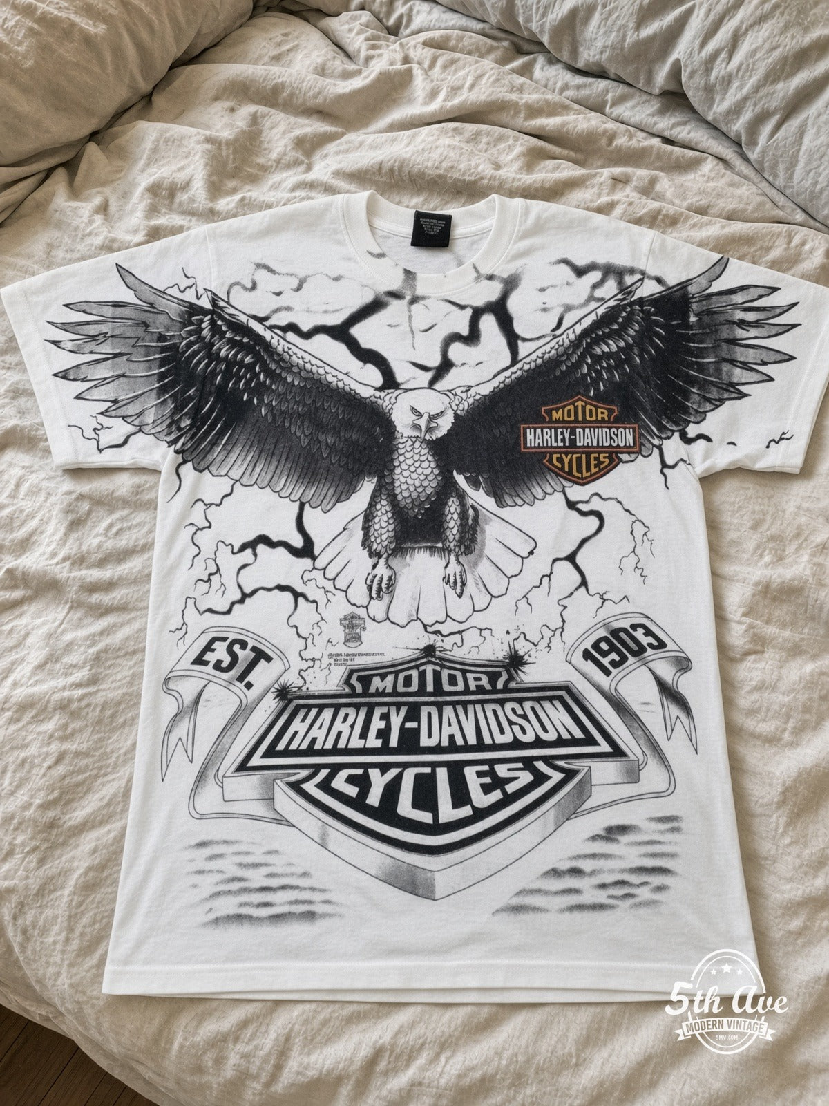 Harley-Davidson Eagle Lightning EST 1903 White all over print vintage tee laid on bed