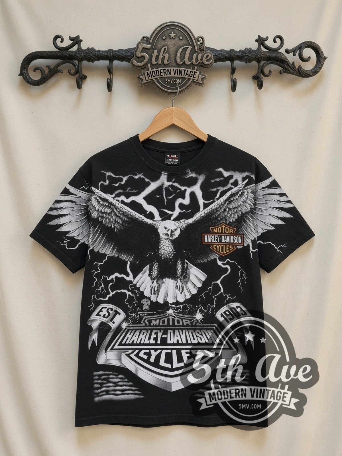 Harley-Davidson Eagle Lightning EST 1903 all-over-print vintage Harley tee in black, front view on a display rack