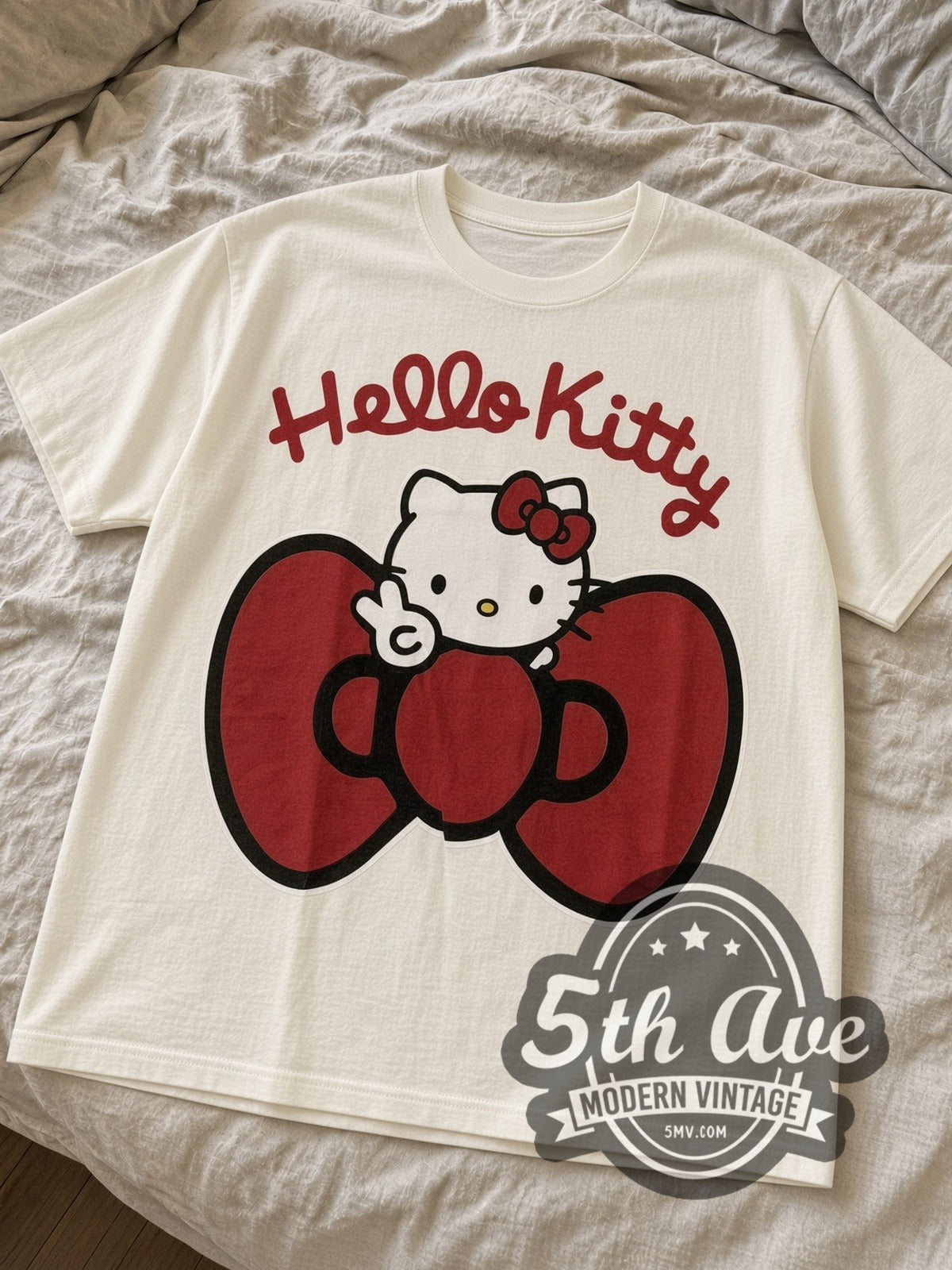 Cream Hello Kitty Big Red Bow Front & Back tee laid flat on linen bed