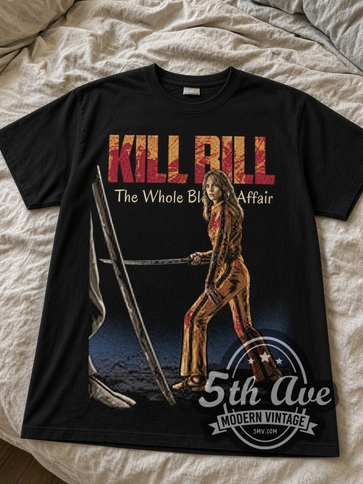 Kill Bill The Bride with Katana Whole Bloody Affair black graphic tee laid flat on linen bed