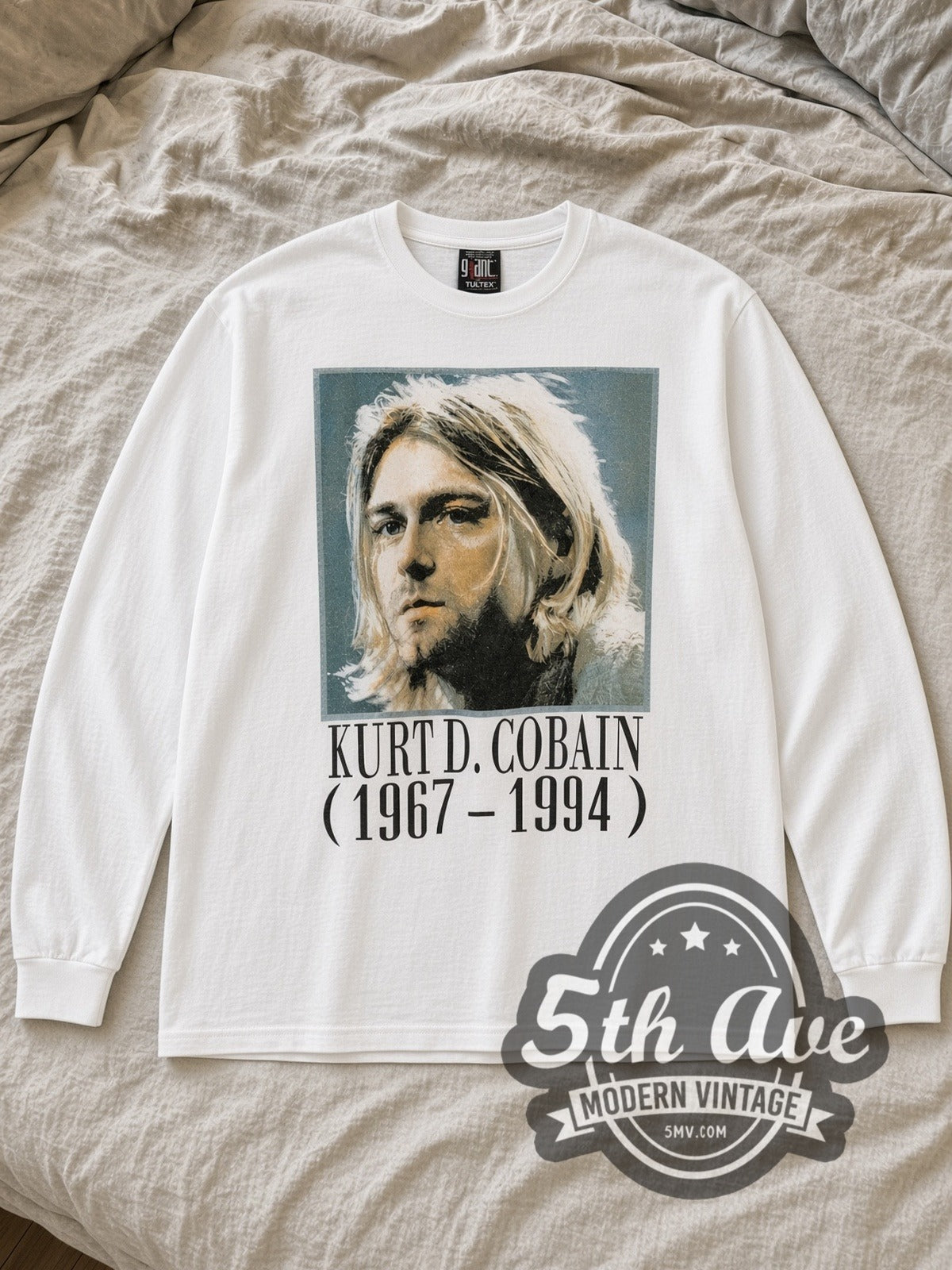 White Kurt Cobain Legacy Tribute Vintage Band T-Shirt laid flat on a linen bed