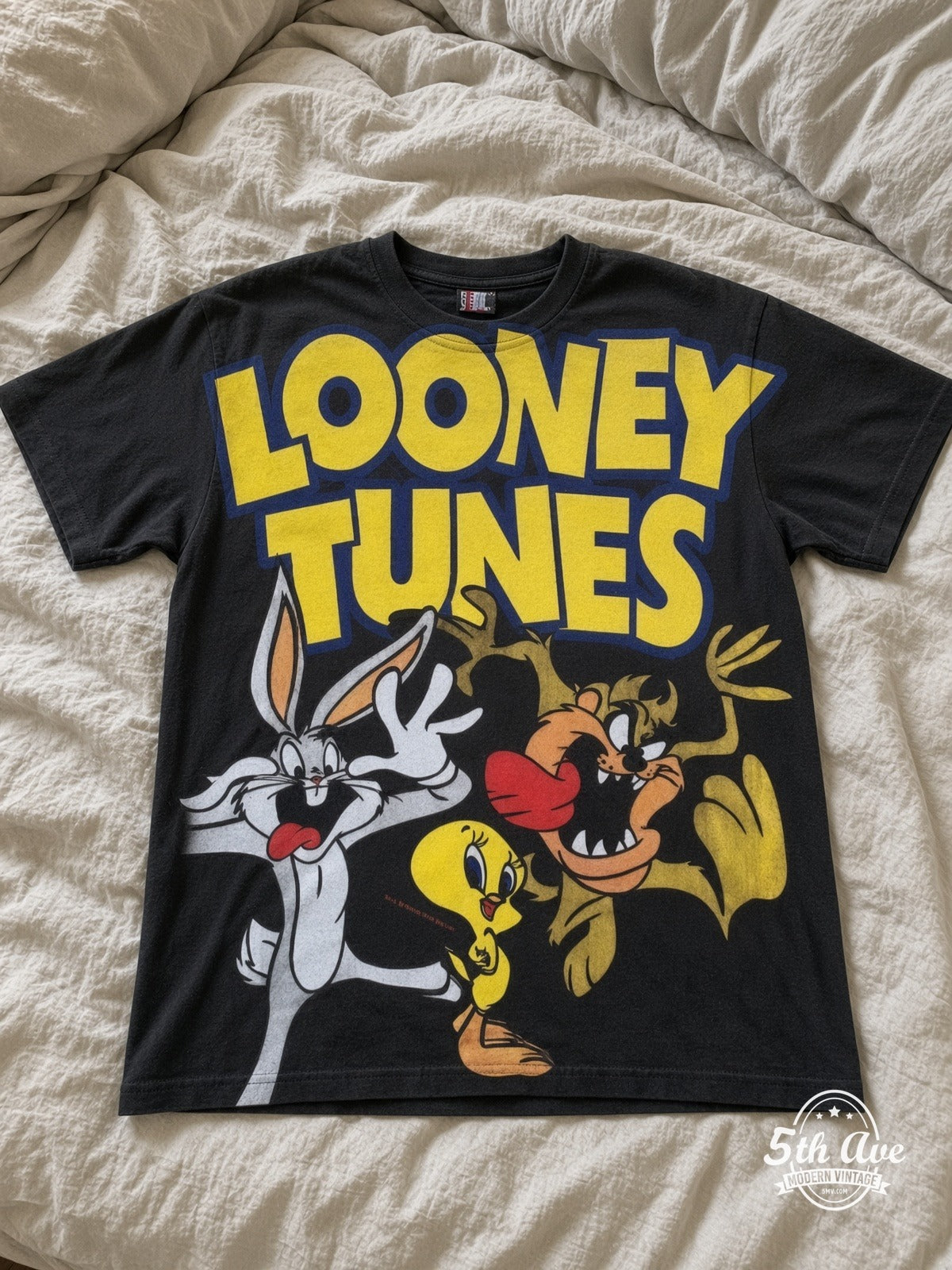 Looney Tunes Logo Bugs Tweety Taz Crew vintage tee laid on bed