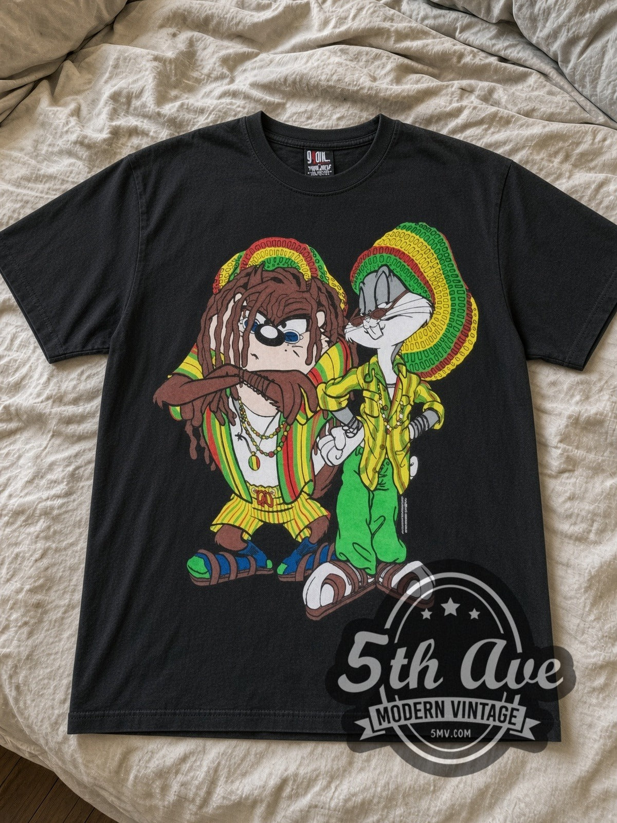 Looney Tunes Rasta Bugs and Taz cartoon tee in black laid flat on a bed, front artwork