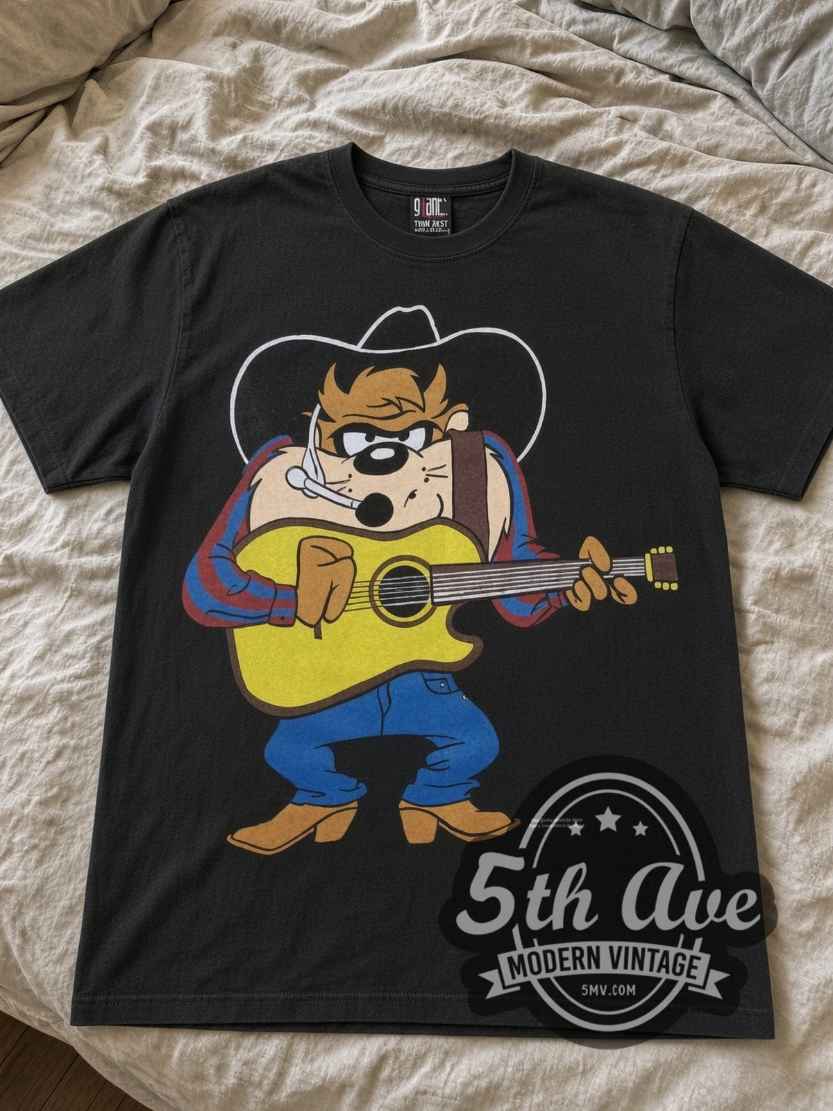Looney Tunes Taz Cowboy Guitar Garth cartoon tee in black laid flat on a bed, front artwork