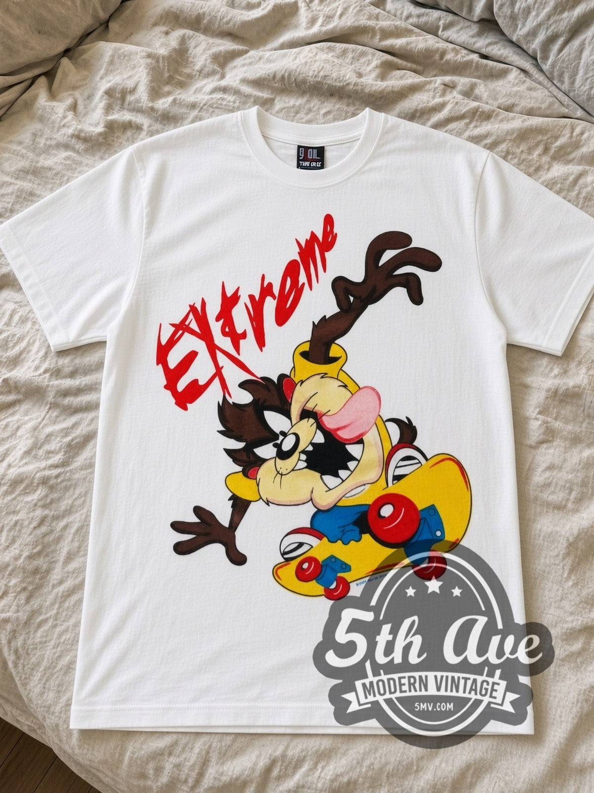 Looney Tunes Taz Extreme Skate cartoon tee in white laid flat on a bed, front artwork