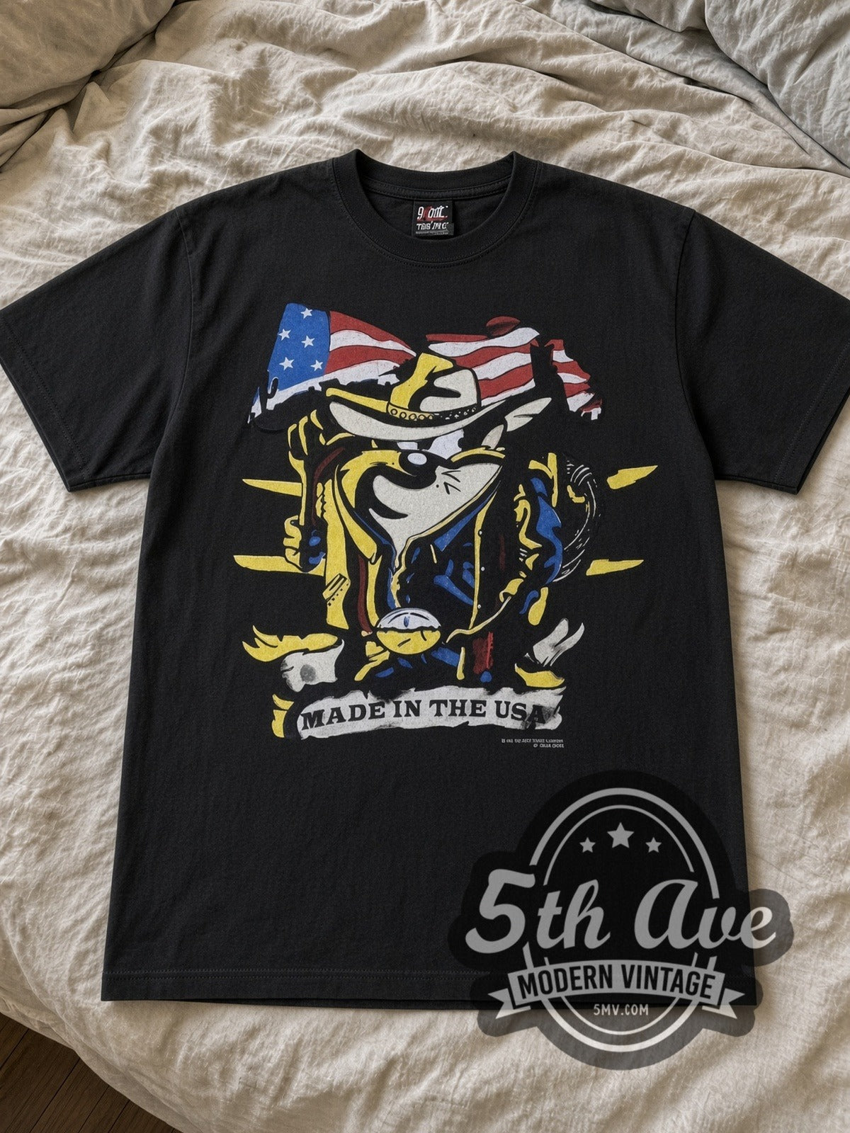 Looney Tunes Taz Made in the USA Cowboy Flag cartoon tee in black laid flat on a bed, front artwork
