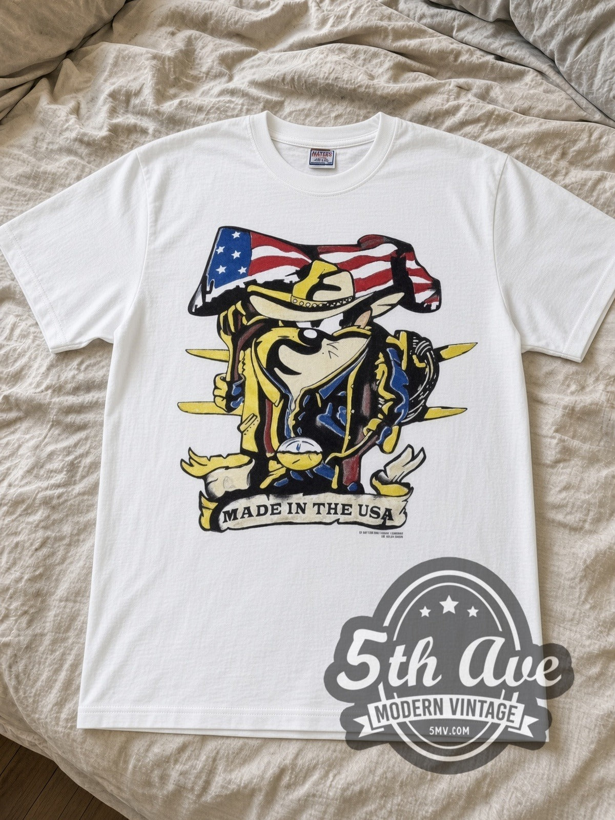 Looney Tunes Taz Made in the USA Cowboy Flag cartoon tee in white laid flat on a bed, front artwork