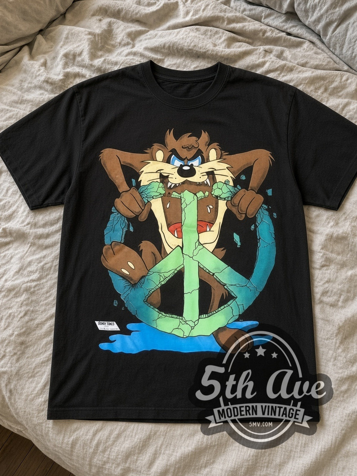 Looney Tunes Taz Peace Sign cartoon tee in black laid flat on a bed, front artwork