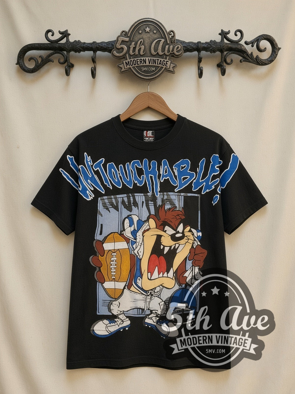 Looney Tunes Taz Untouchable Football all-over-print vintage cartoon t-shirt in black, front view on a display rack