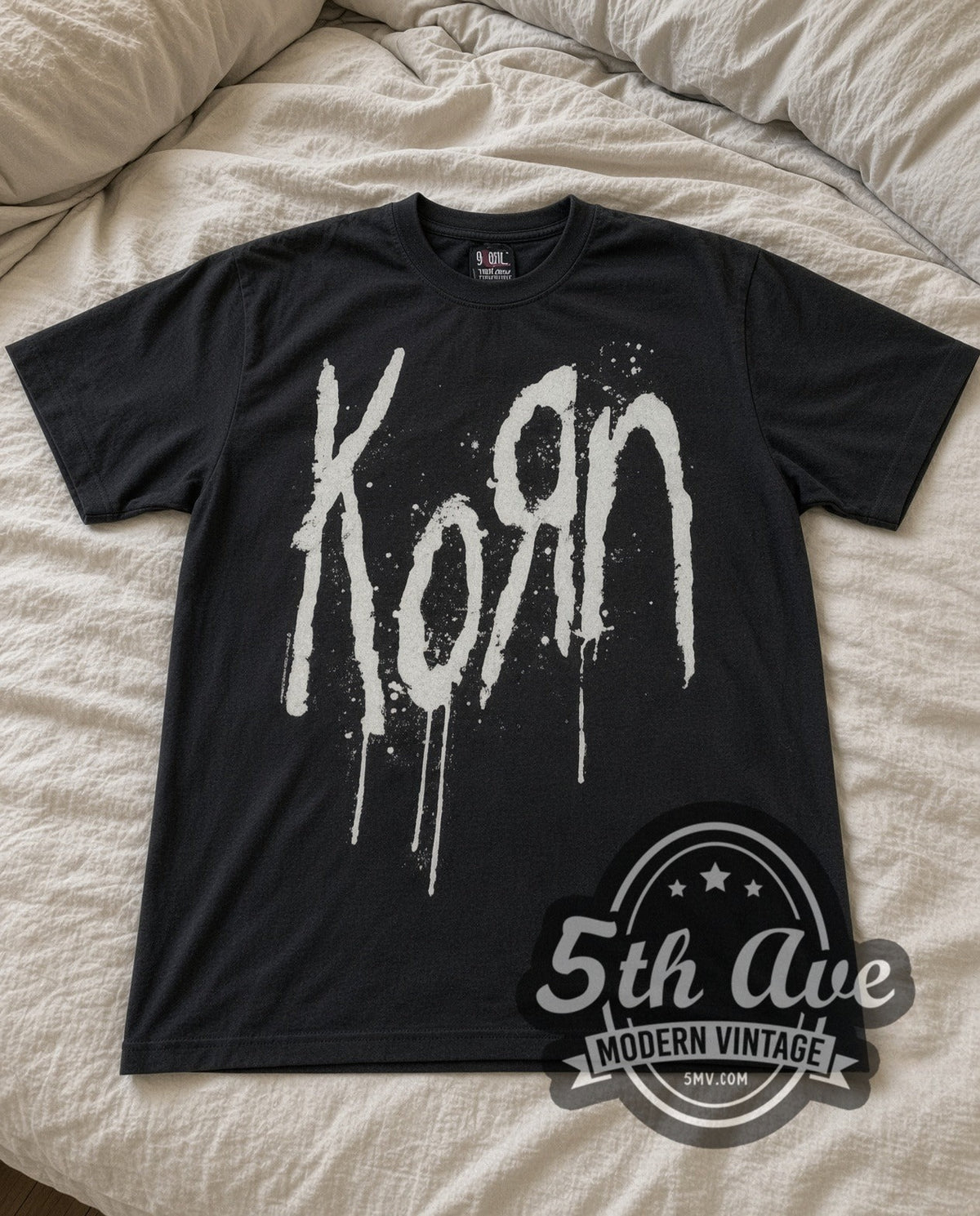Korn Drip Logo vintage band t-shirt in black laid flat on a bed, front artwork