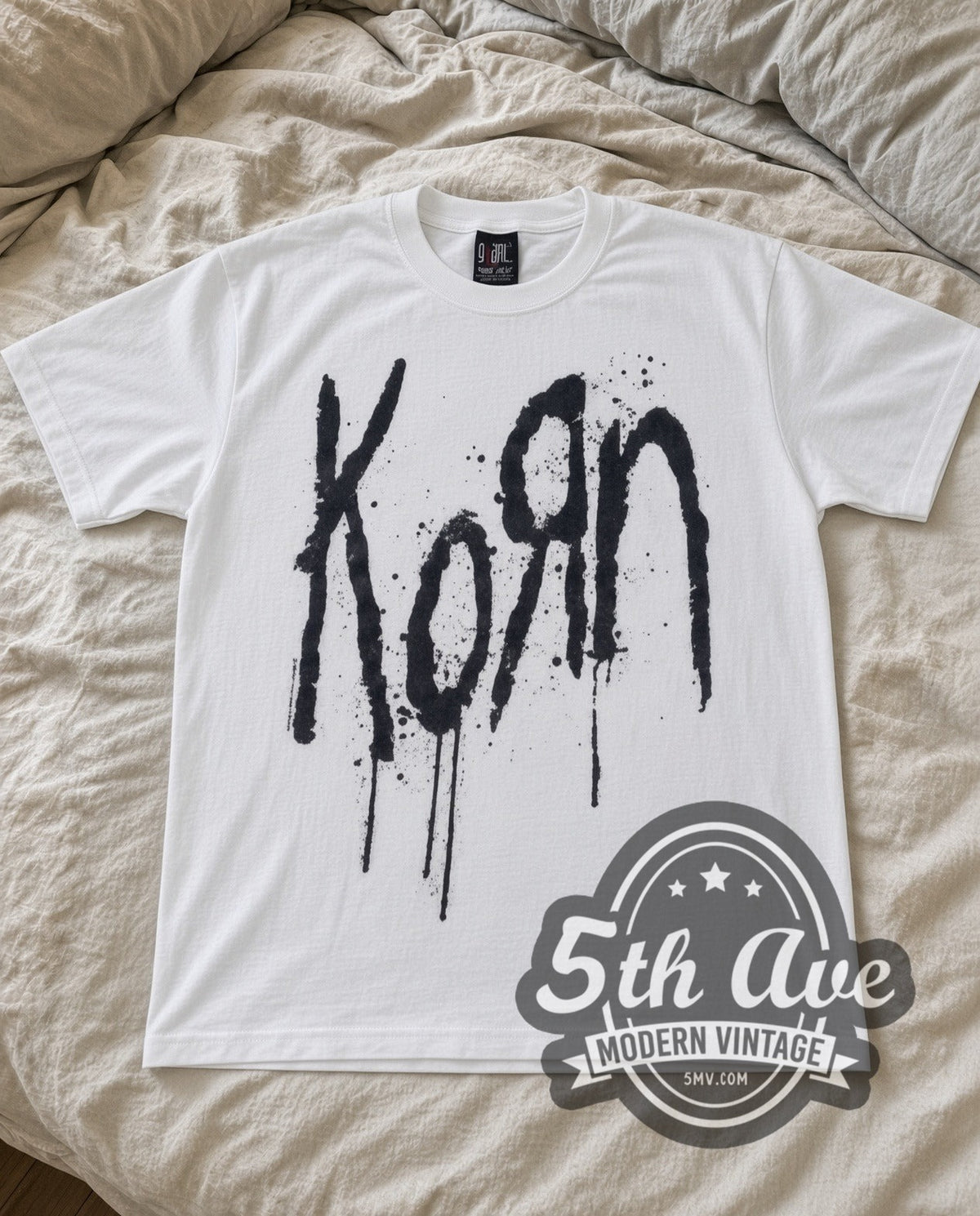 Korn Drip Logo vintage band t-shirt in white laid flat on a bed, front artwork