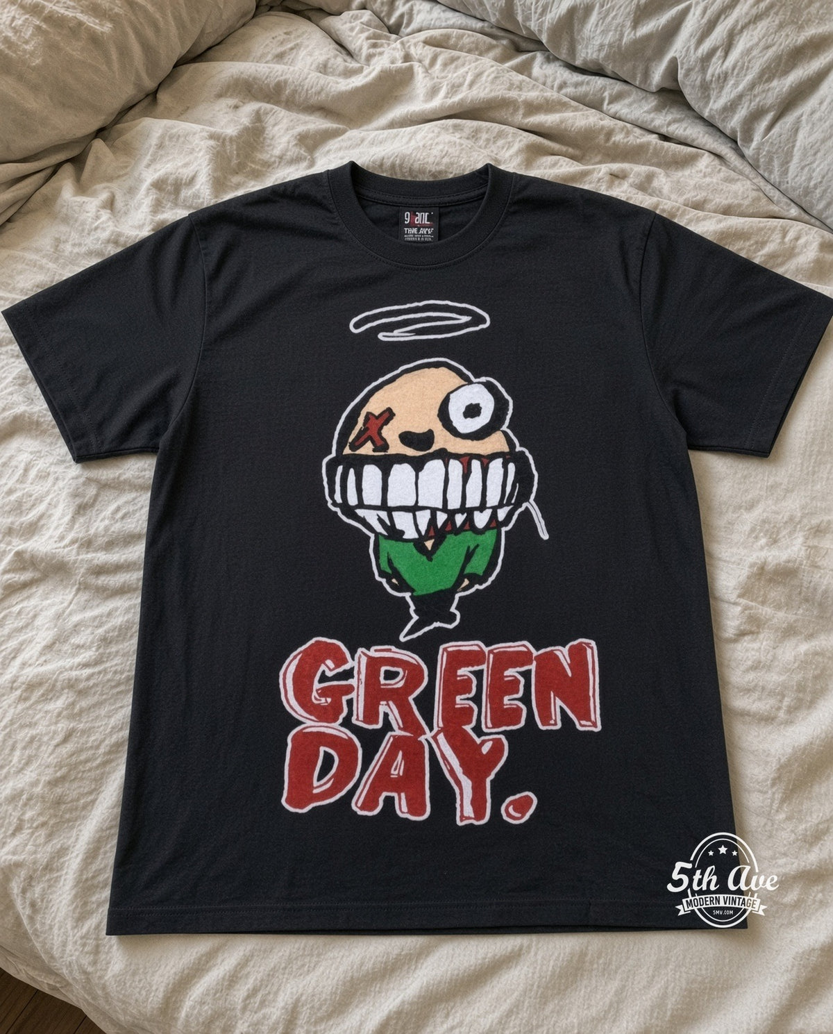Green Day Smiley vintage band t-shirt in black laid flat on a bed, front artwork