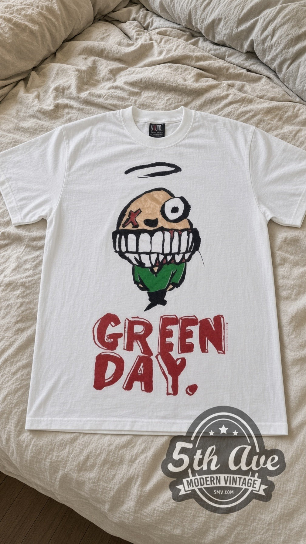 Green Day Smiley vintage band t-shirt in white laid flat on a bed, front artwork