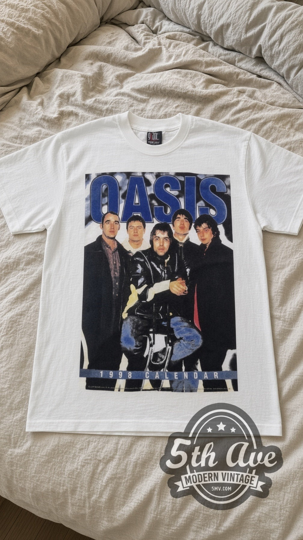 Oasis Tour Calendar vintage band t-shirt in white laid flat on a bed, front artwork