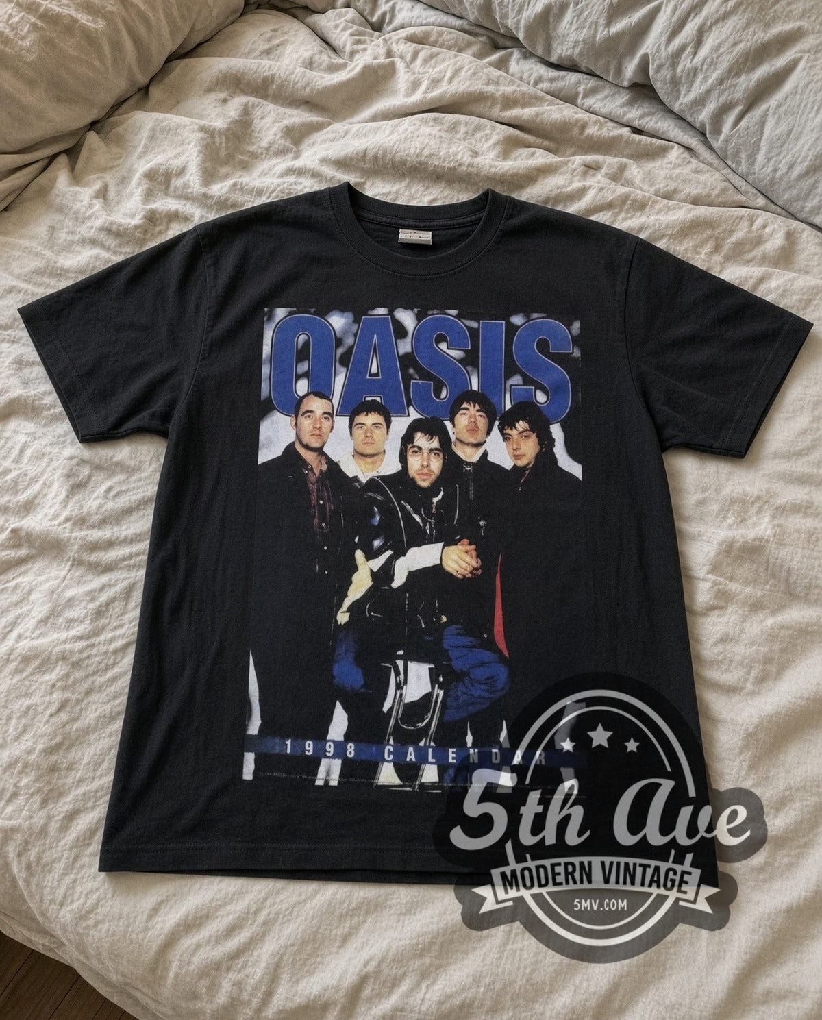Oasis Tour Calendar vintage band t-shirt in black laid flat on a bed, front artwork