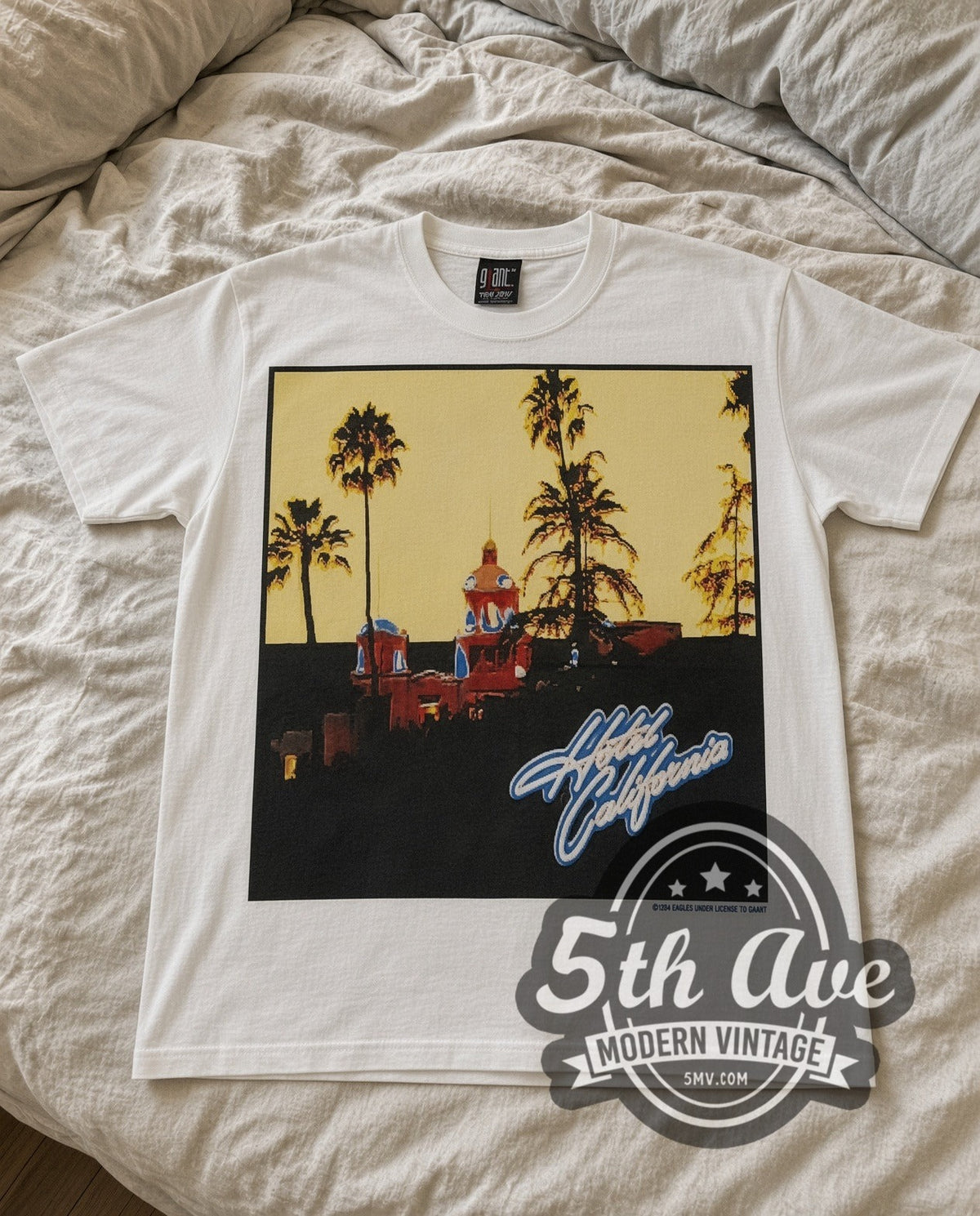 Eagles Hotel Sign vintage band t-shirt in white laid flat on a bed, front artwork