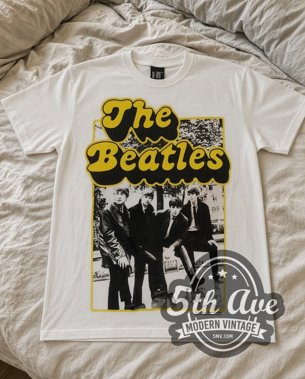 The Beatles Cartoon Band vintage band t-shirt in white laid flat on a bed, front artwork