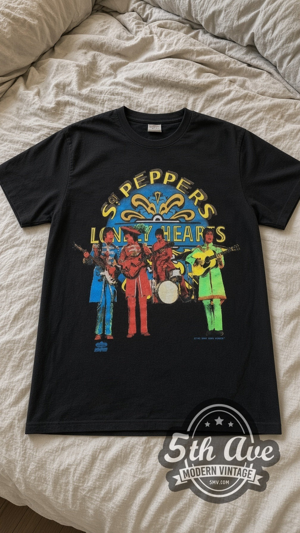 The Beatles Sgt Peppers vintage band t-shirt in black laid flat on a bed, front artwork