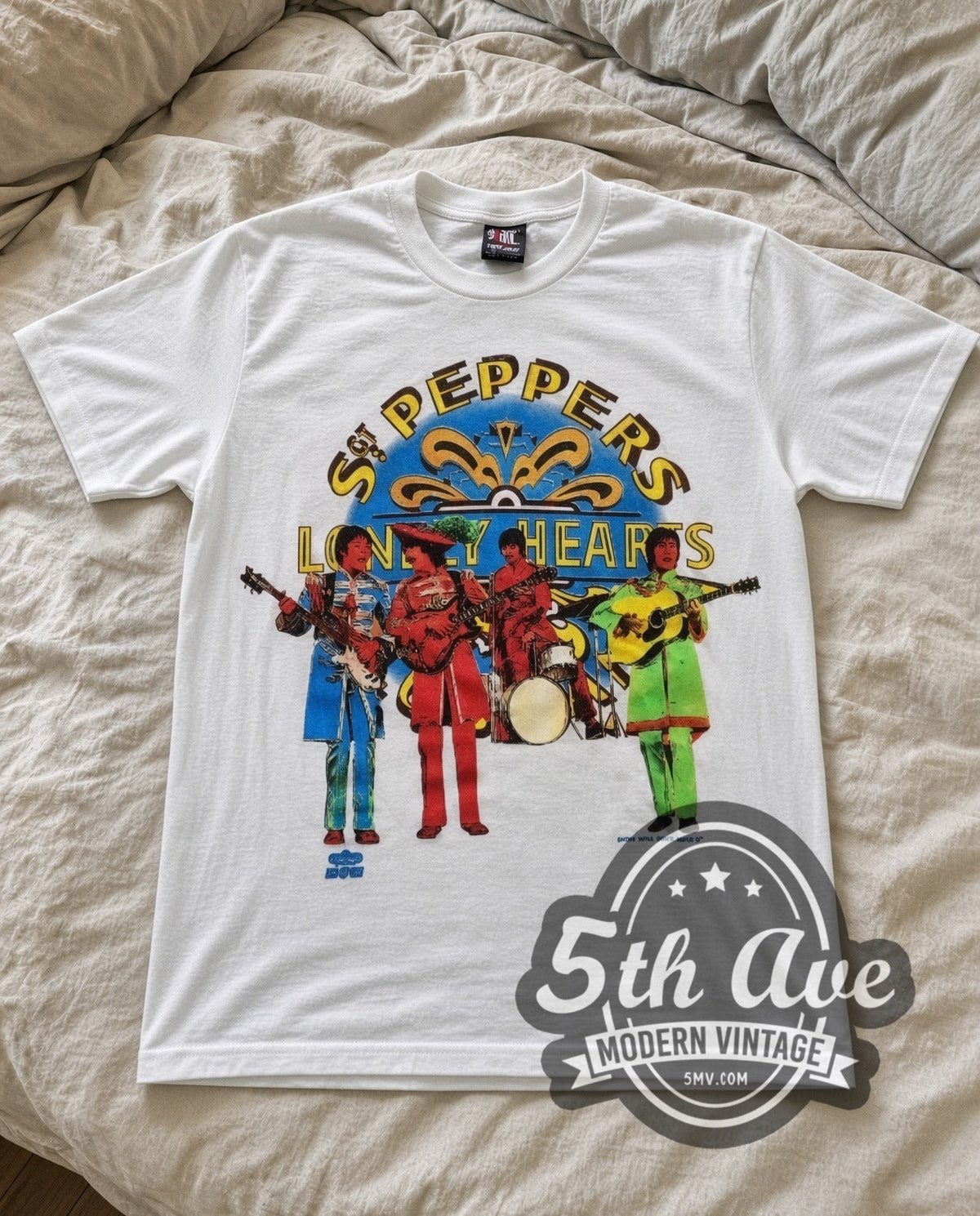The Beatles Sgt Peppers vintage band t-shirt in white laid flat on a bed, front artwork