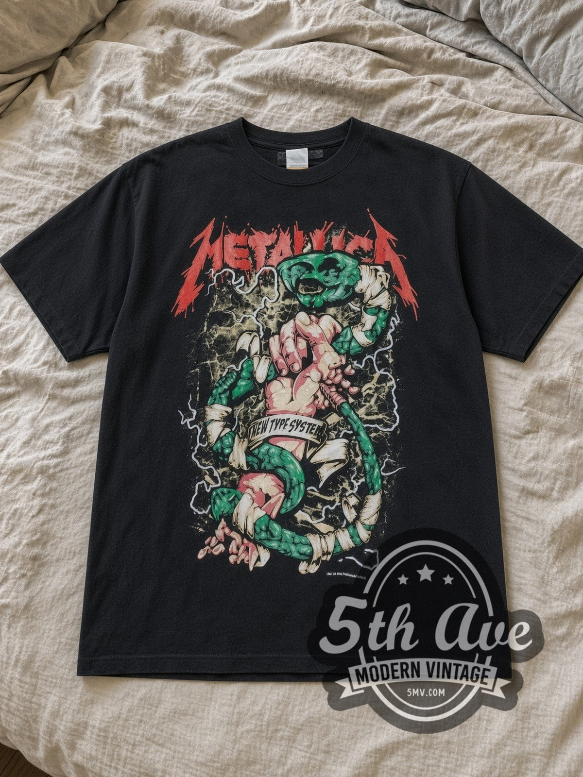 Black Metallica New Type System Fist Green Snake Vintage Band T-Shirt laid flat on a linen bed