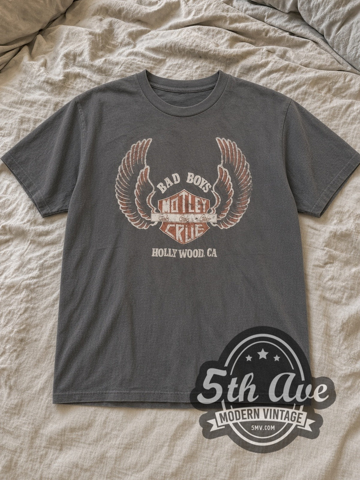 Charcoal Mötley Crüe Bad Boys Girls Girls Girls Winged Shield Vintage Band T-Shirt laid flat on a linen bed