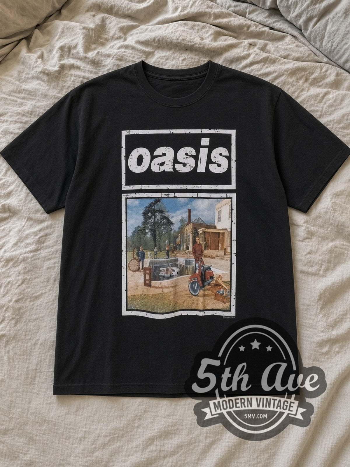 Black Oasis Be Here Now Vintage Band T-Shirt laid flat on a linen bed