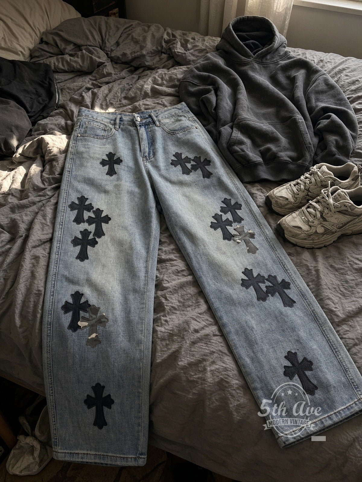 Light Wash Black + Camo Cross Patch Streetwear Jeans laid on bed