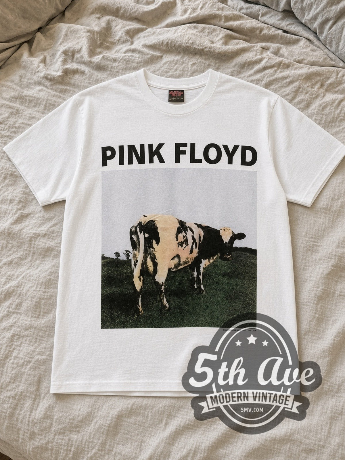 White Pink Floyd Atom Heart Mother Cow Front Vintage Band T-Shirt laid flat on a linen bed
