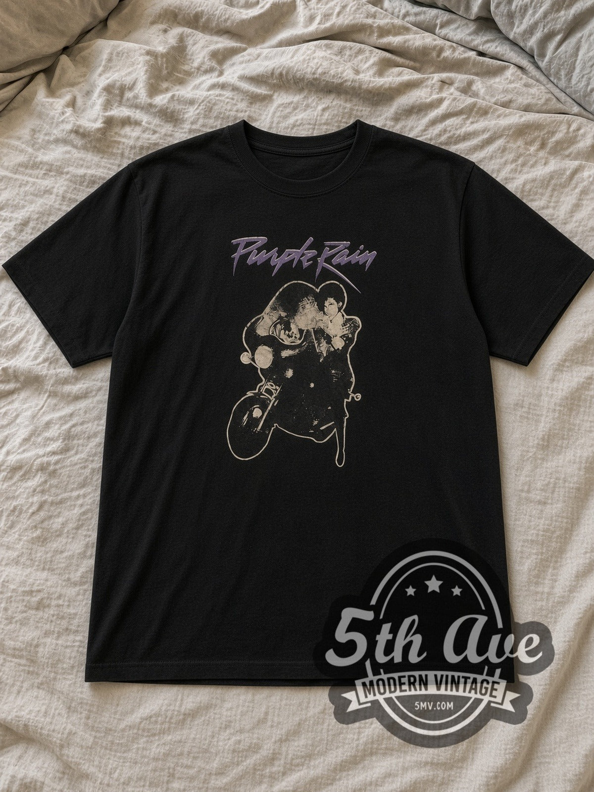 Black Prince Purple Rain Script Motorcycle Vintage Band T-Shirt laid flat on a linen bed