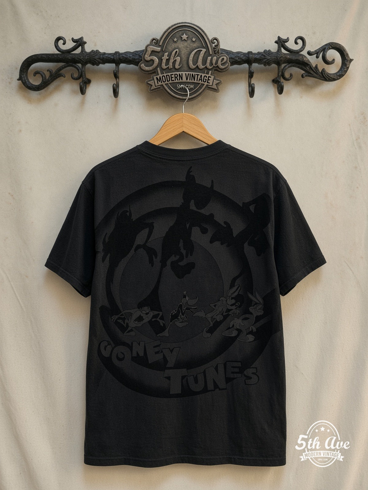 Looney Tunes Blue Circle Logo all-over-print vintage cartoon tee in black, back view on a display rack