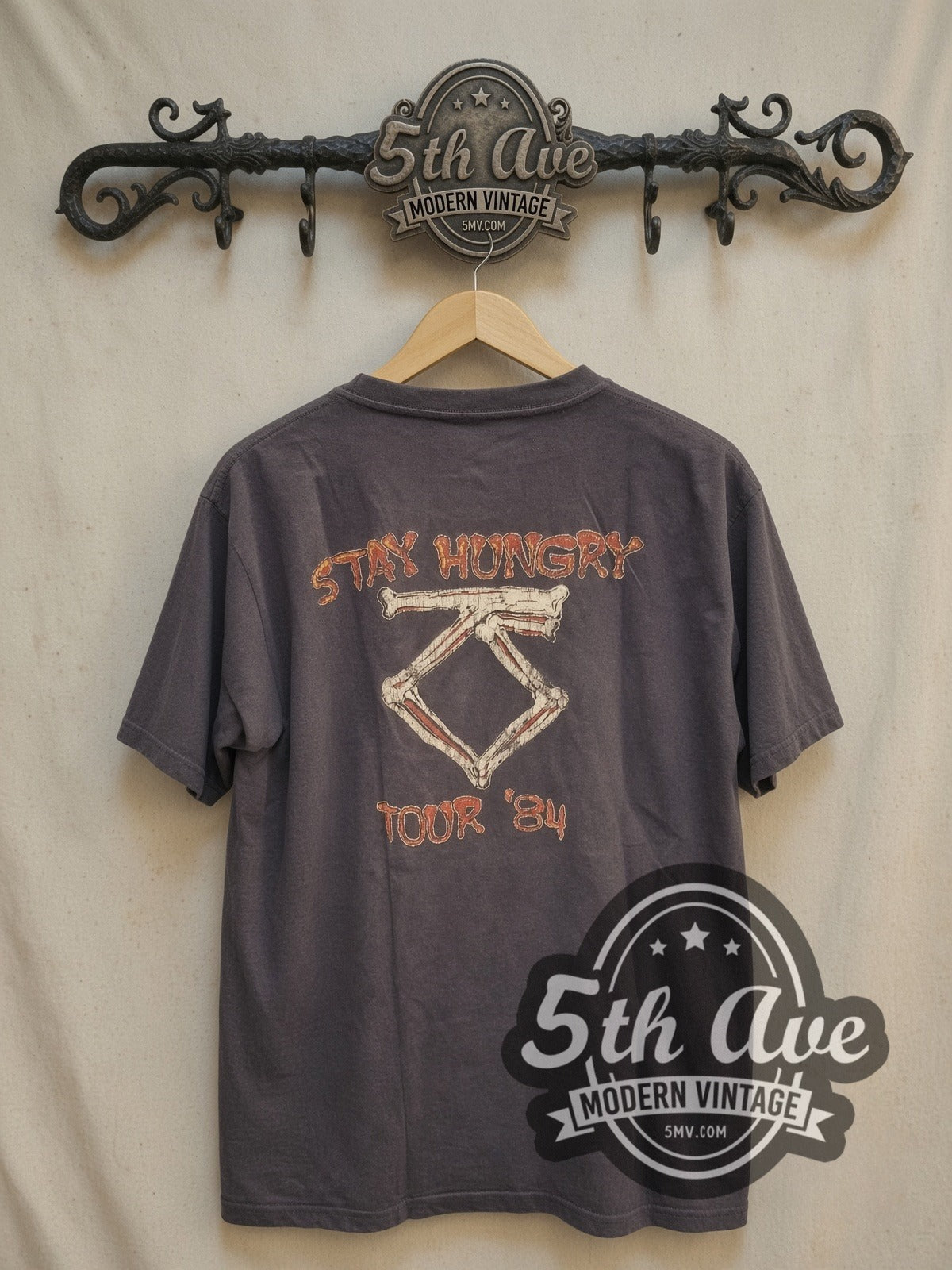 Twisted Sister Stay Hungry Dee Snider Biting Bone vintage band t-shirt, back view on a display rack
