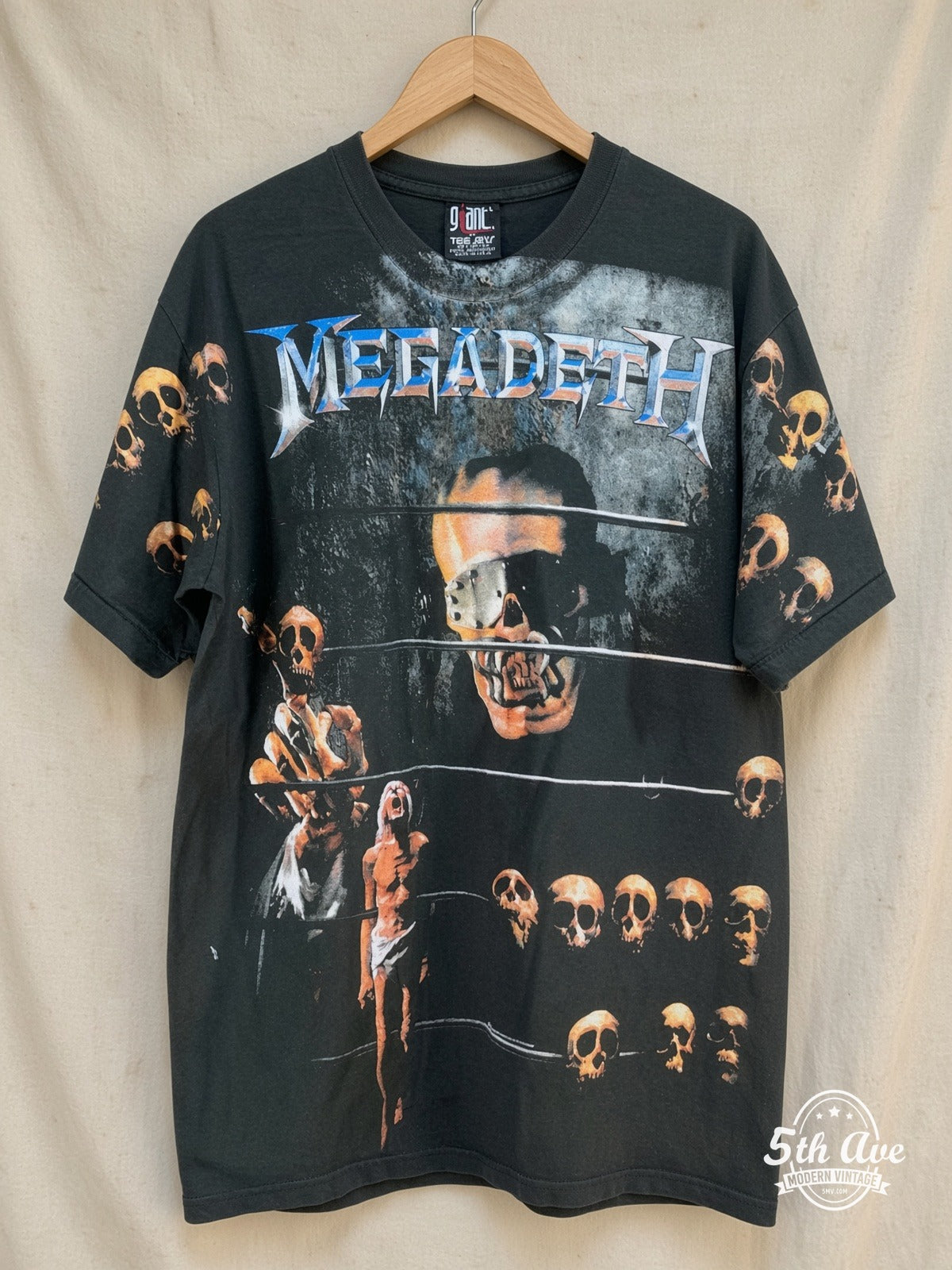 Megadeth – Vic Rattlehead Multi Skull All Over Print – Vintage Band T-Shirt — front on locked cream ornate 5th Ave rack