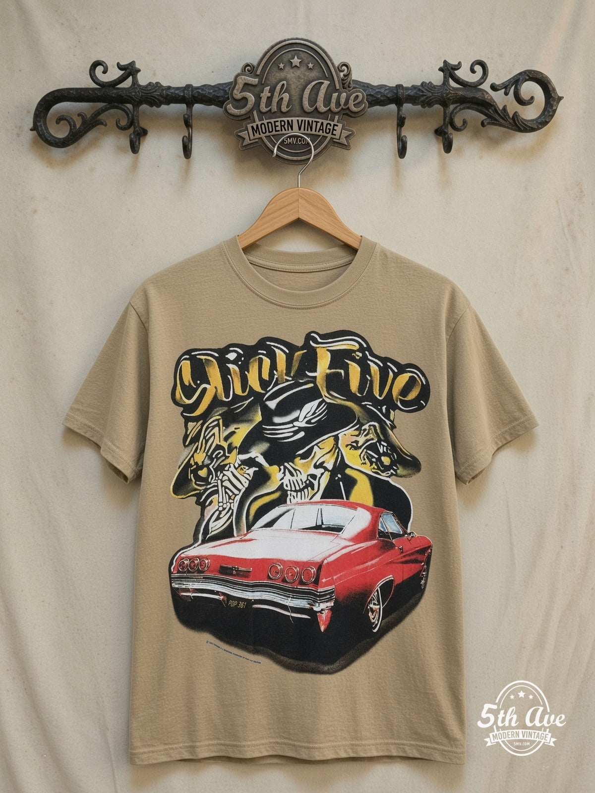 Rollin Hard Slick Five Lowrider graphic tee in sand, front view on a display rack