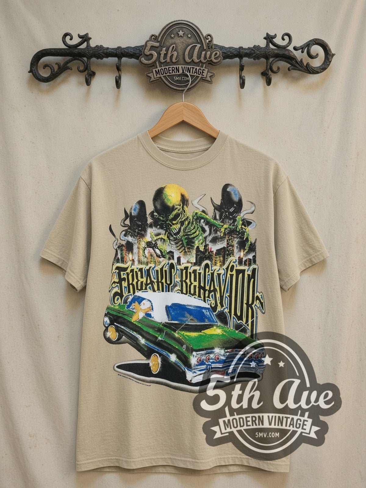 Rollin Hard Freaky Behavior Lowrider vintage graphic tee in sand, front view on a display rack