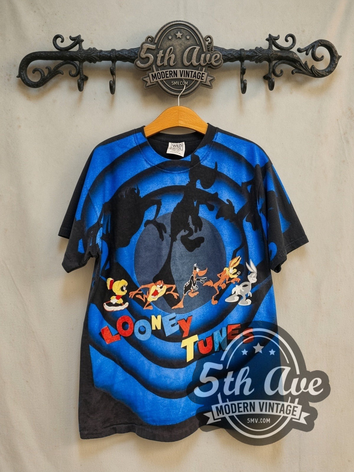 Looney Tunes Blue Circle Logo all-over-print vintage cartoon tee in black, front view on a display rack