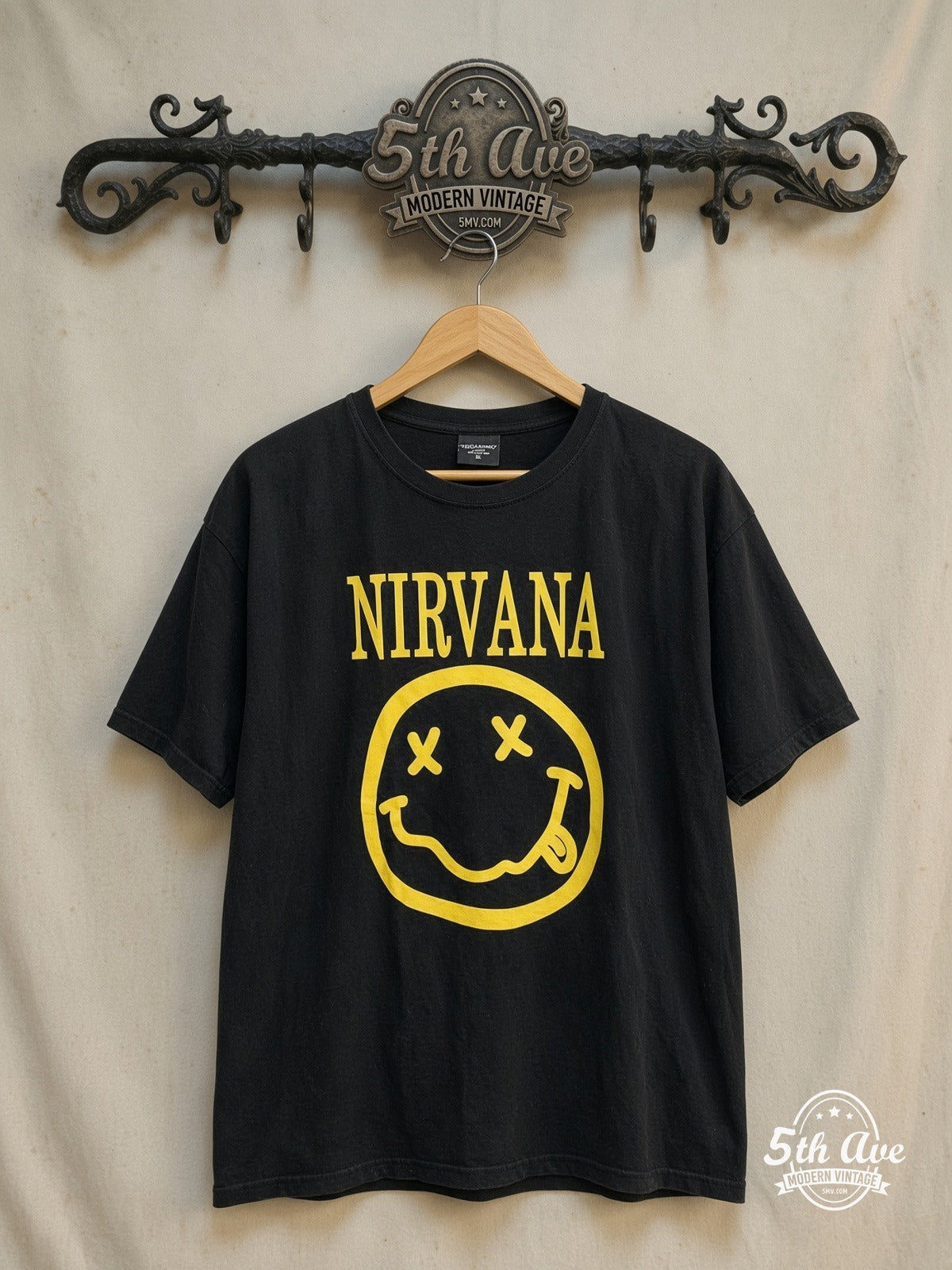 Nirvana – Classic Yellow Smiley Face Logo – Vintage Band T-Shirt — front on locked cream ornate 5th Ave rack