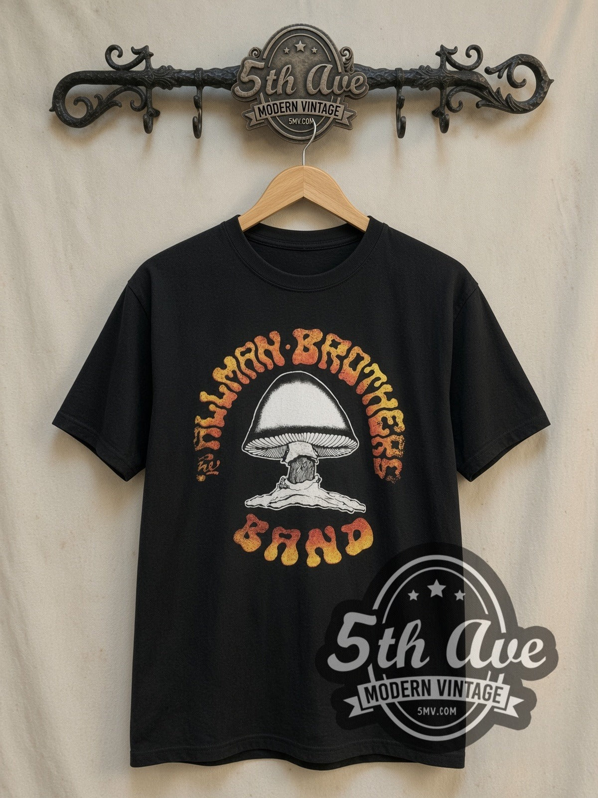 The Allman Brothers Band Mushroom Logo Orange Gradient Text vintage band t-shirt, front view on a display rack