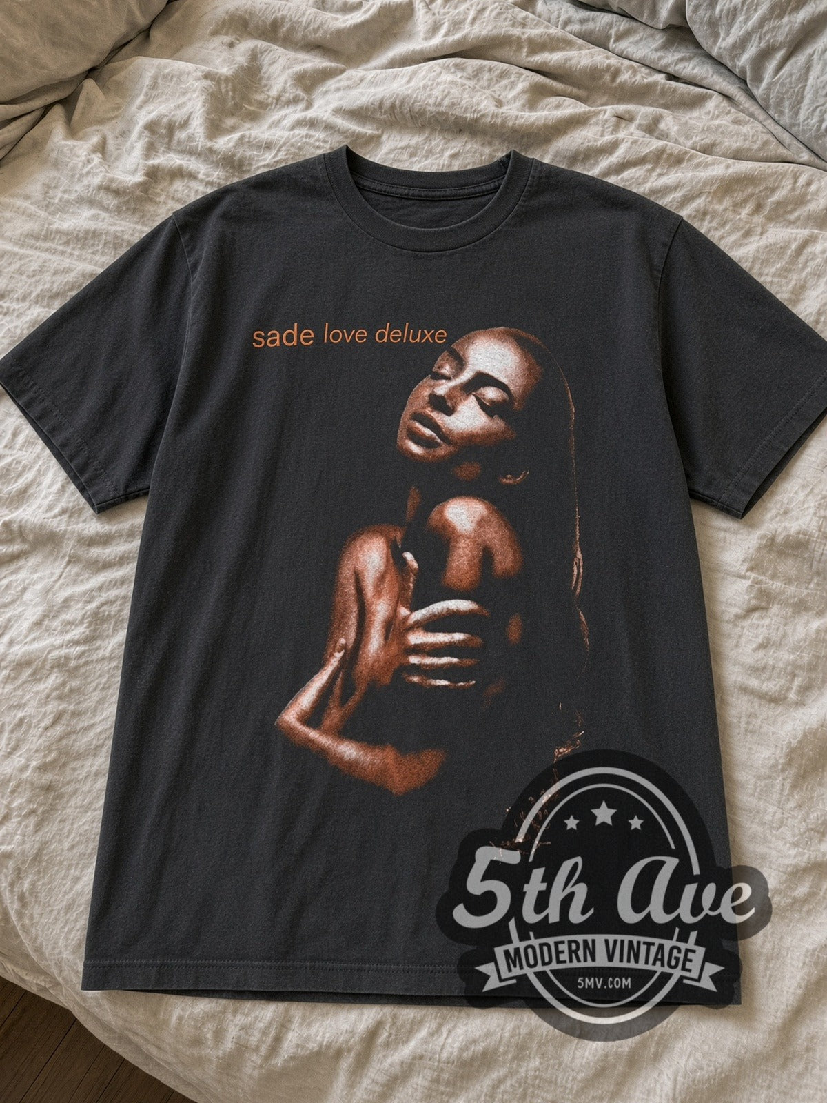 Black Sade Love Deluxe tee laid flat on linen bed