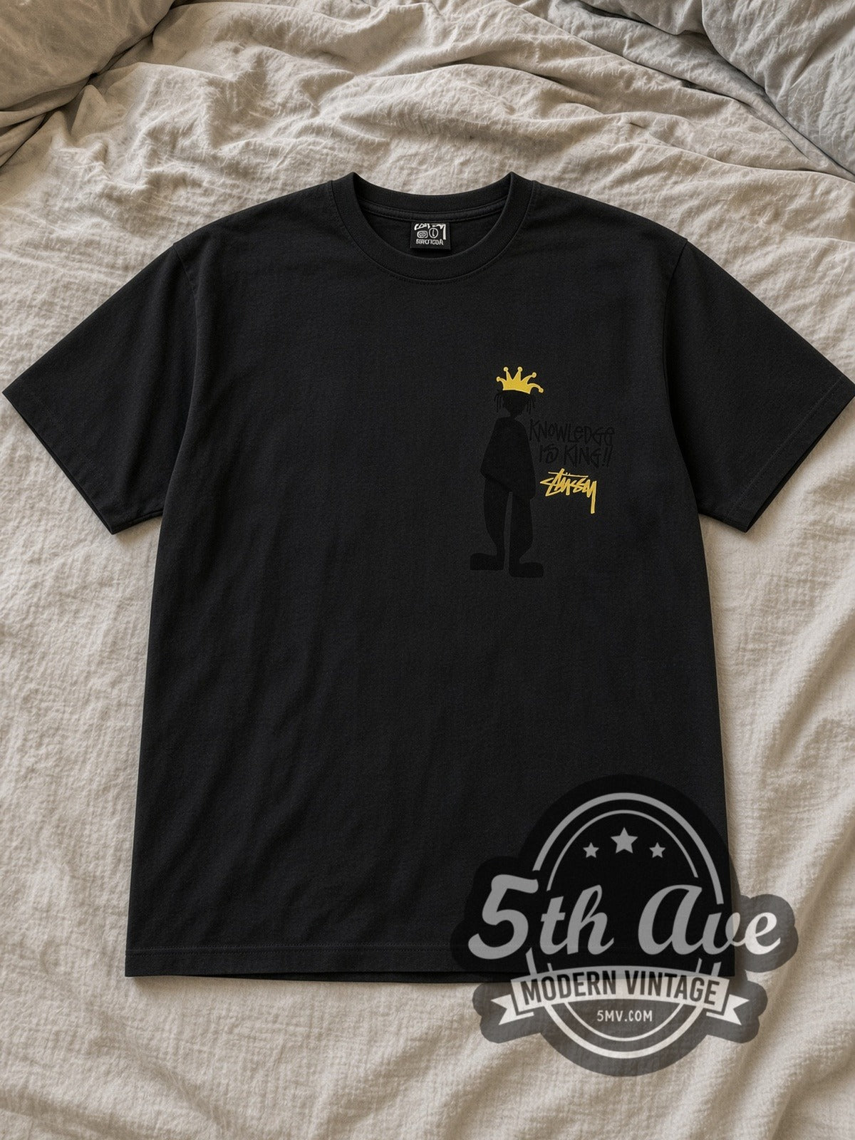 Black Stussy Knowledge Is King Vintage Graphic T-Shirt laid flat on a linen bed