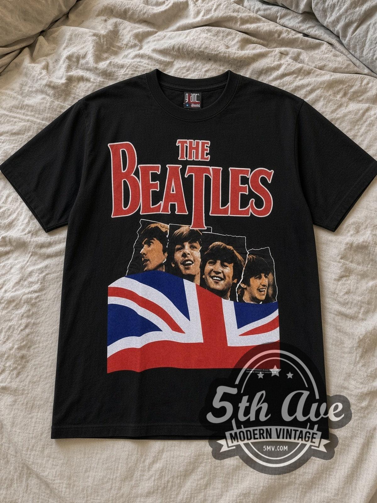 Black The Beatles Union Jack Red Logo Mop Top Vintage Band T-Shirt laid flat on a linen bed