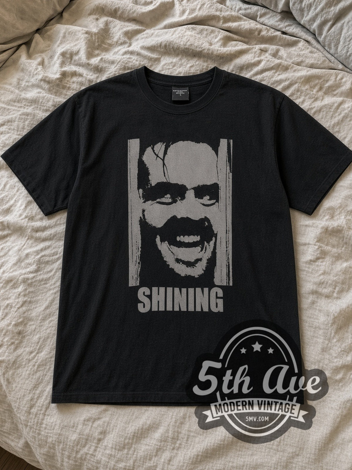 Black The Shining Jack Torrance Vintage Movie T-Shirt laid flat on a linen bed