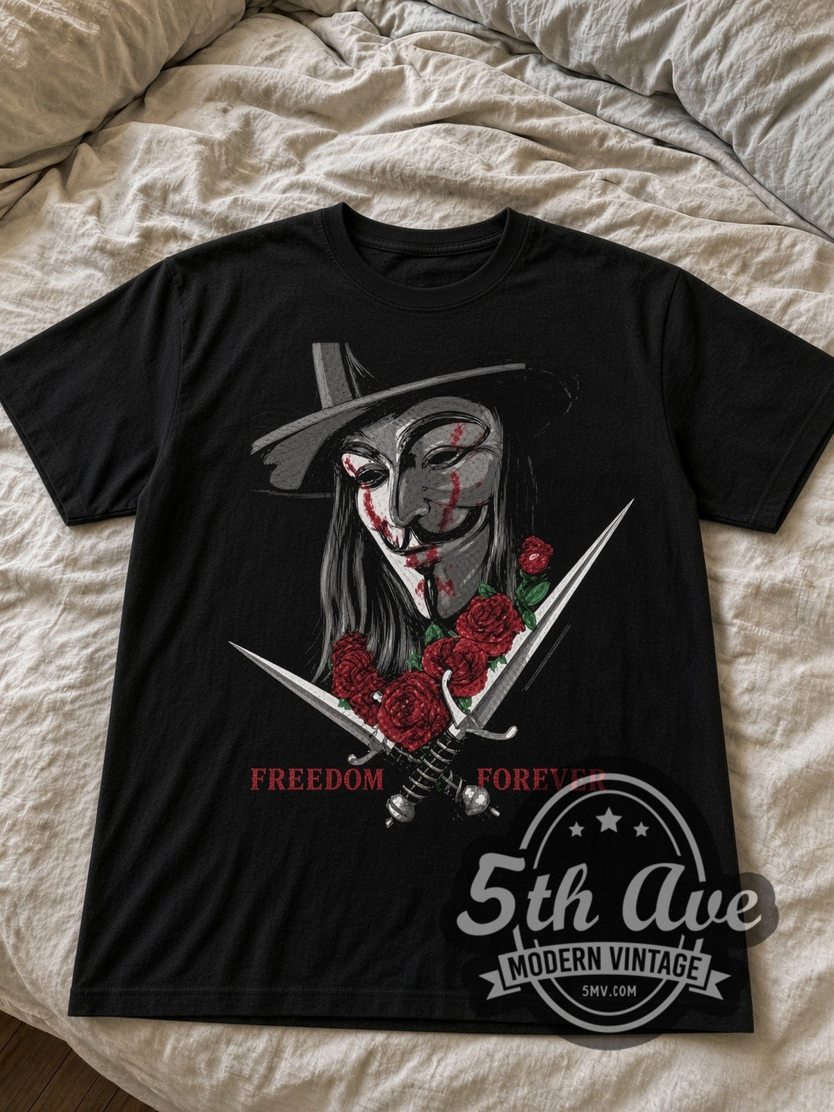 V for Vendetta Guy Fawkes Mask with Daggers black graphic tee laid flat on linen bed