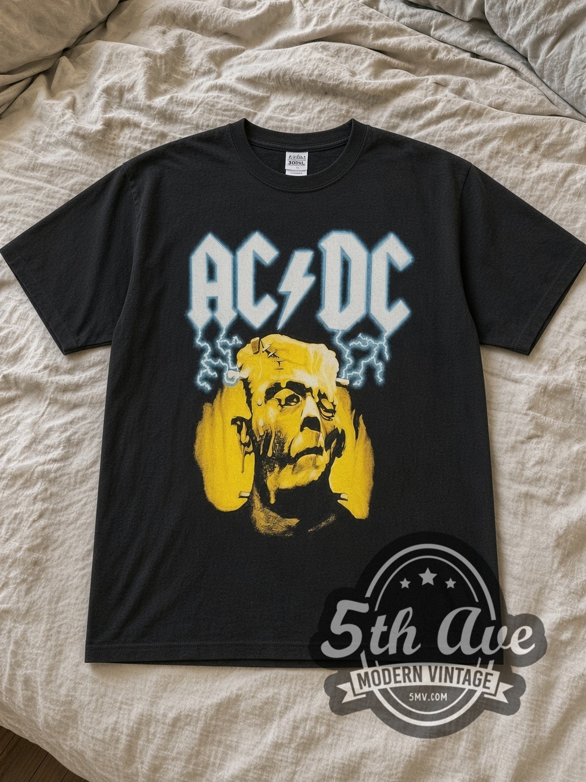 Black AC/DC Meltdown Vintage Band T-Shirt laid flat on a linen bed
